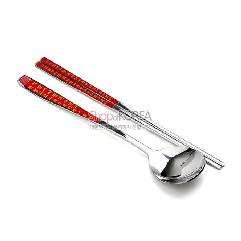 붉은색 배경 위에 금색 훈민정음 글자 문양이 인쇄된 금속 젓가락과 수저 1인용 세트.
