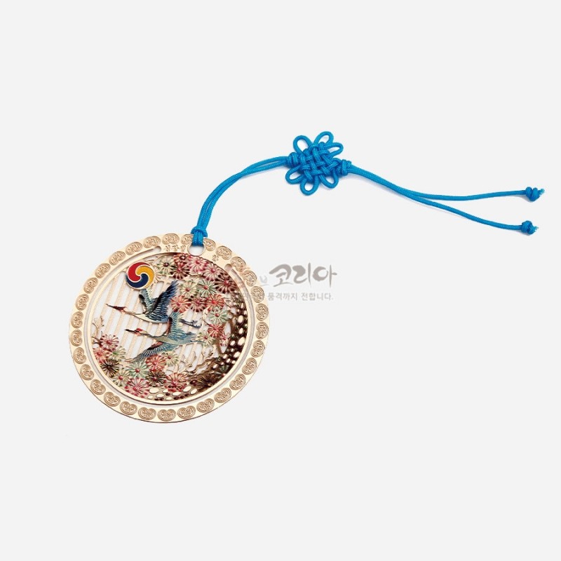 금속 재질 둥근 액자형 테두리에 십장생 자개 상감 문양을 넣고, 청색 전통 매듭 끈으로 장식한 금색 책갈피. 금속 재질 둥근 액자형 테두리에 십장생 자개 상감 문양을 넣고, 청색 전통 매듭 끈으로 장식한 금색 책갈피.