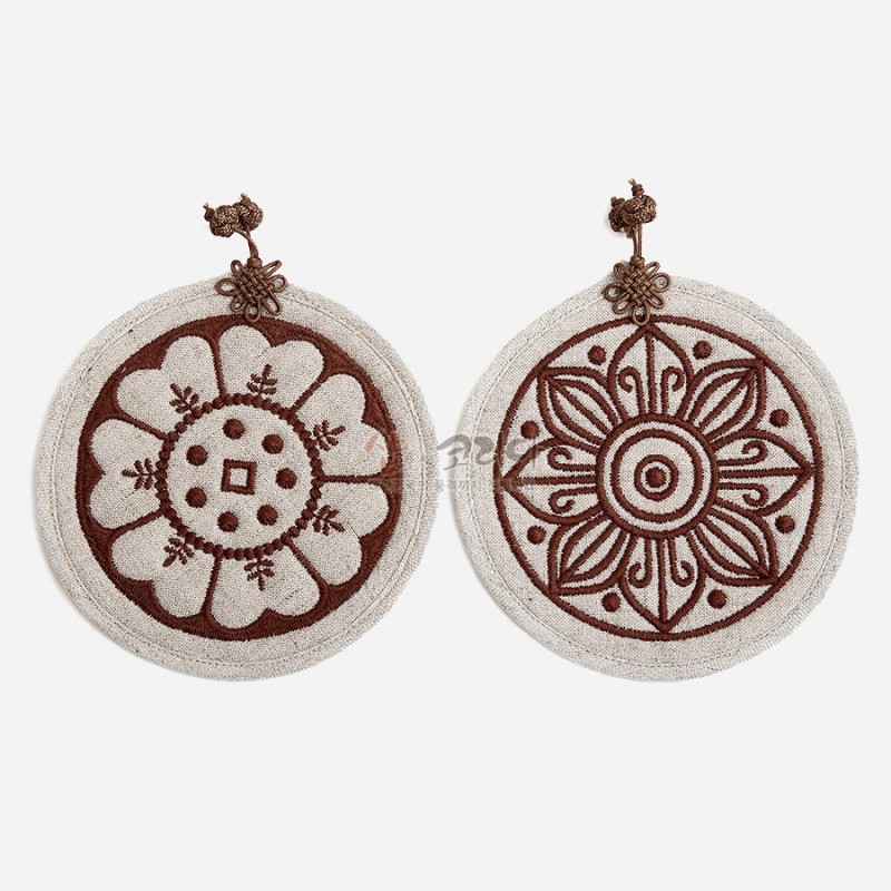 백색 천 소재 위에 갈색 자수로 고구려·백제 수막새 꽃문양을 표현한 원형 컵받침 2P 세트, 상단 매듭 장식 포인트.