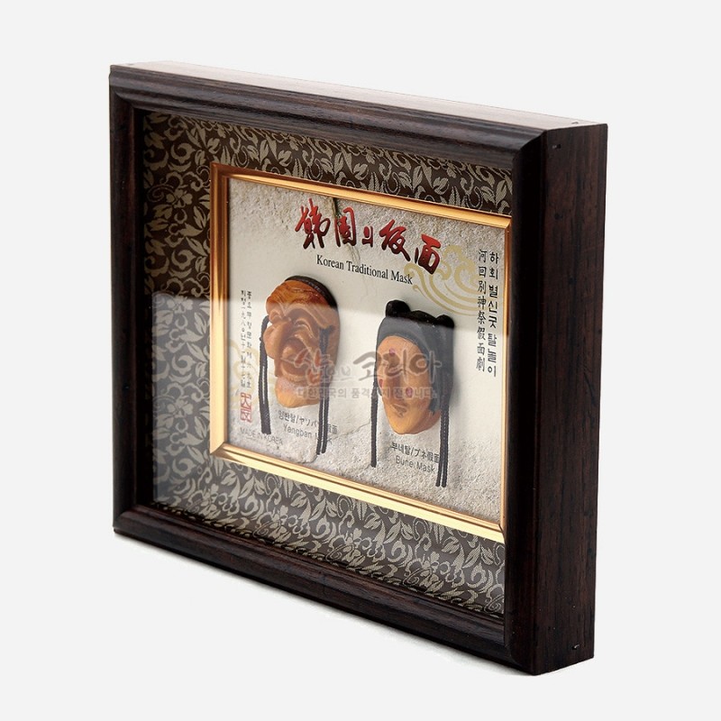 나무 프레임과 유리 커버 속에 황갈색 하회탈 미니어처가 배치된 액자형 장식, 배경 당초무늬와 금색 테두리 장식이 특징인 인테리어 소품. 나무 프레임과 유리 커버 속에 황갈색 하회탈 미니어처가 배치된 액자형 장식, 배경 당초무늬와 금색 테두리 장식이 특징인 인테리어 소품.