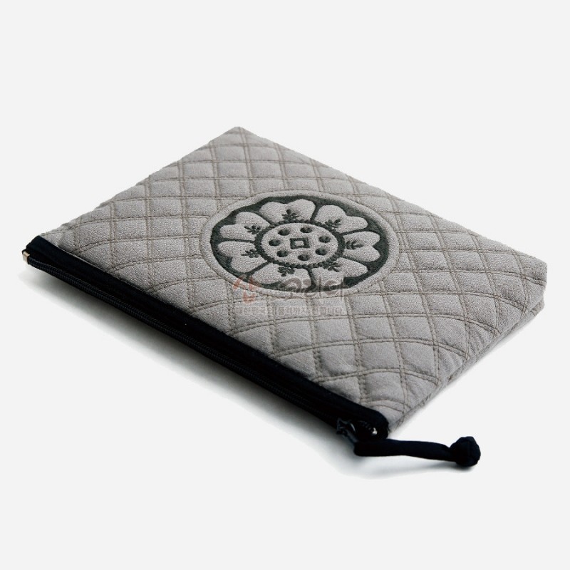 회색 누빔 원단 위에 흑색 백제 수막새 문양 자수와 검은 지퍼 장식이 어우러진 파우치. 회색 누빔 원단 위에 흑색 백제 수막새 문양 자수와 검은 지퍼 장식이 어우러진 파우치.