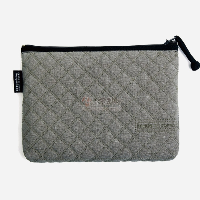 회색 패브릭 소재에 누빔 기법으로 사각 격자 무늬를 더하고 검은 지퍼로 마감한 파우치. 회색 패브릭 소재에 누빔 기법으로 사각 격자 무늬를 더하고 검은 지퍼로 마감한 파우치.