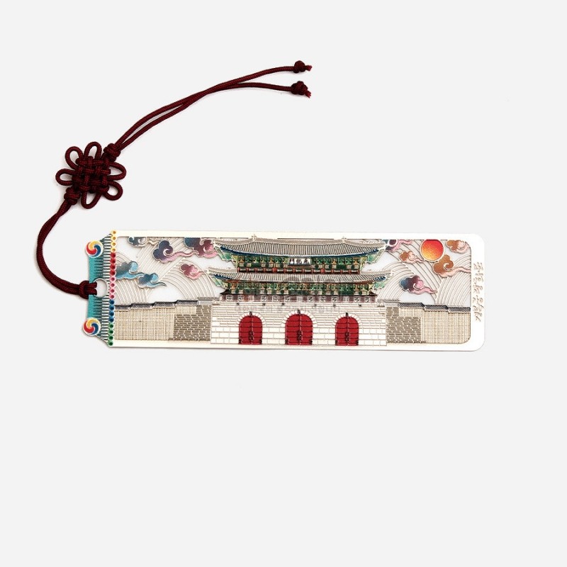 금속 재질에 광화문과 구름, 해 문양을 정교하게 채색한 직사각 책갈피와 붉은 전통 매듭 장식.