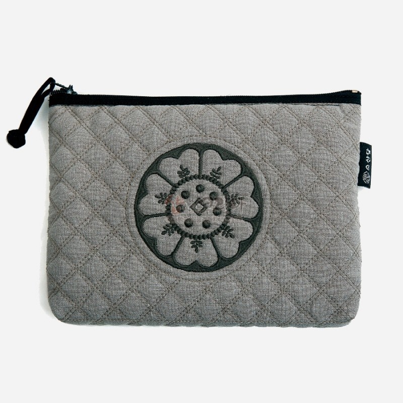퀼팅 처리된 그레이 패브릭 위에 흑색 백제 수막새 문양 자수 장식이 돋보이는 지퍼 파우치.