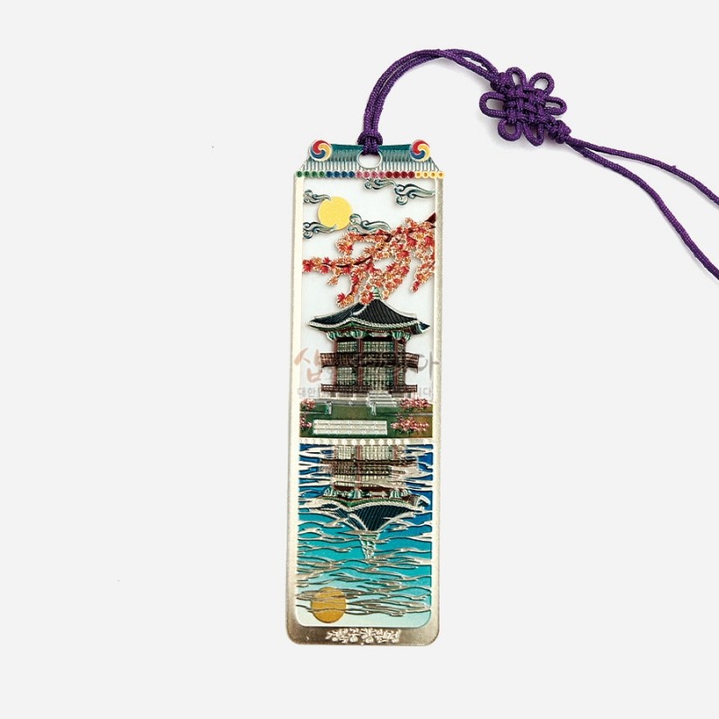 금속 소재에 채색 기법으로 궁궐 정자와 호수 반영을 표현하고, 벚꽃과 노을 문양이 더해진 자개 장식 책갈피.