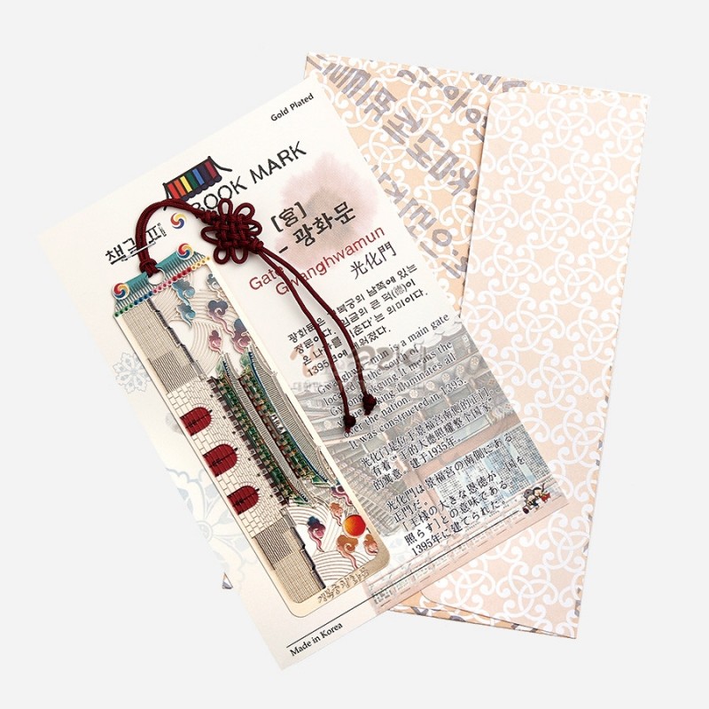 금장 금속 재질에 광화문과 단청 문양을 섬세하게 새긴 책갈피, 붉은 전통 매듭 장식과 다채로운 색상의 장식끈이 어우러진 디자인.