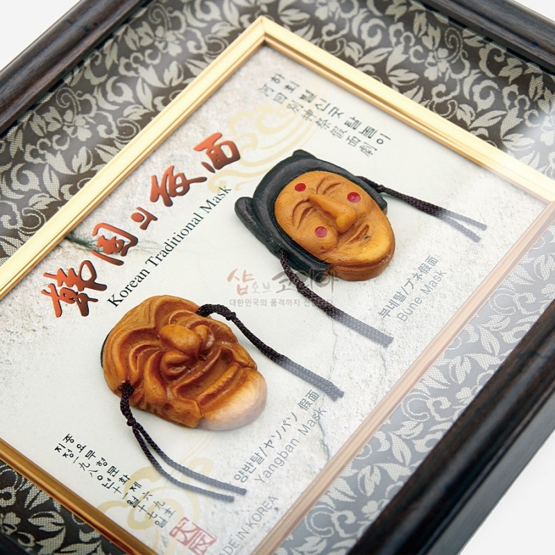 당초무늬 패턴의 직물 배경과 금색 내부 틀 속에 목조 하회탈 장식이 배치된 직사각 액자. 당초무늬 패턴의 직물 배경과 금색 내부 틀 속에 목조 하회탈 장식이 배치된 직사각 액자.