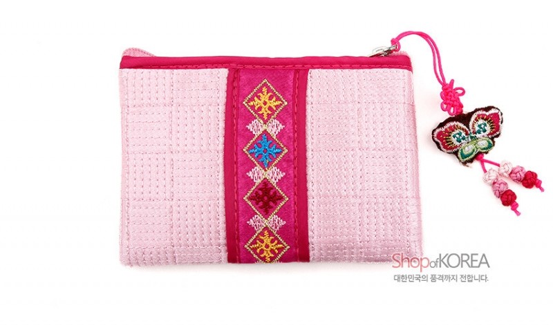 연분홍 색상의 누비 비단으로 제작된 동전지갑, 중앙 오방색 기하학 자수와 나비 노리개 매듭 장식이 특징인 디자인. 연분홍 색상의 누비 비단으로 제작된 동전지갑, 중앙 오방색 기하학 자수와 나비 노리개 매듭 장식이 특징인 디자인.