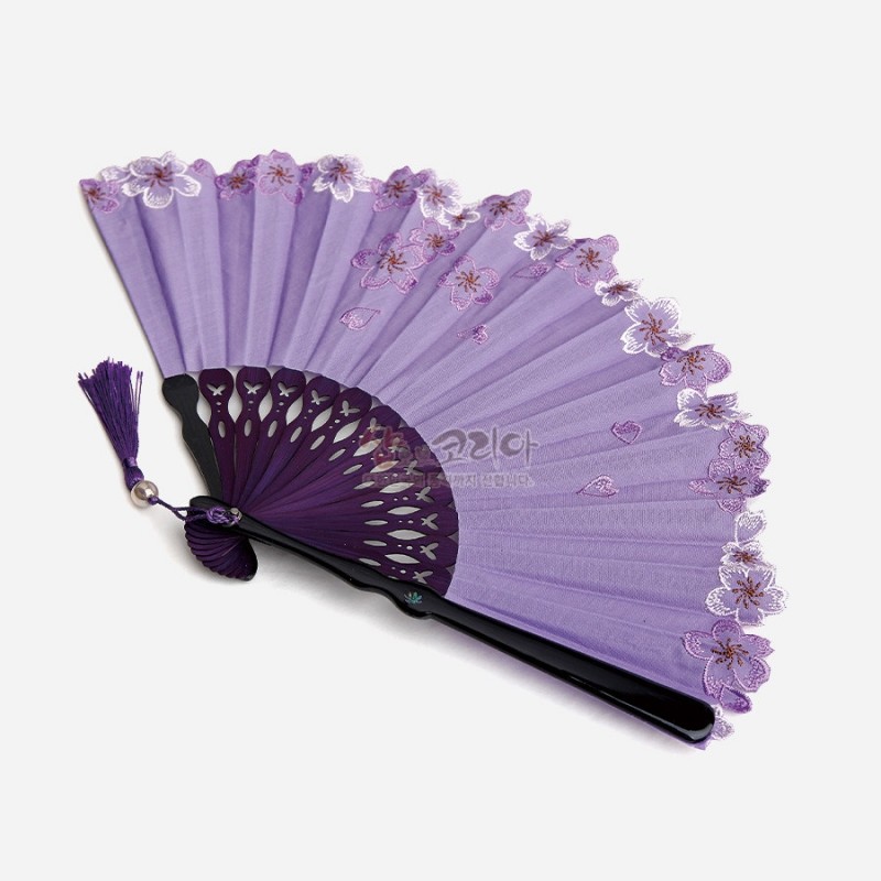 자색 비단 부채살에 분홍·흰 매화 자수 문양이 수놓인 접이식 부채, 장식 매듭 술과 구멍 장식 대나무살이 조화를 이룬 디자인.