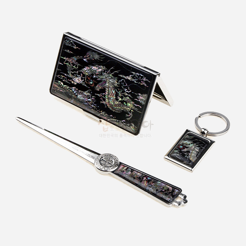 검은 바탕 위 자개 상감 용 문양이 들어간 금속 명함집·지칼·키링 3종 세트.