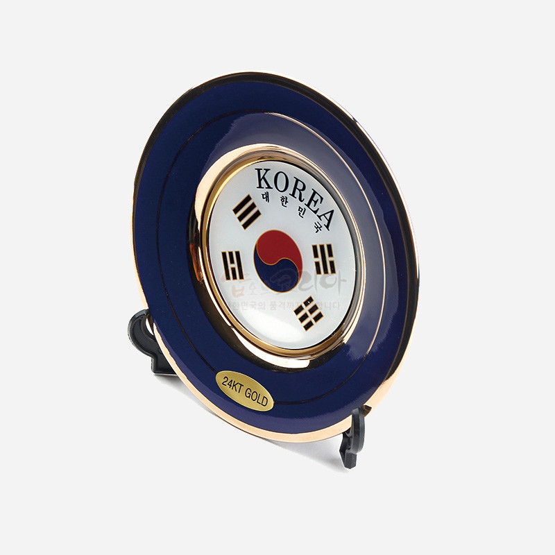 금도금 금속 프레임에 청색 에나멜을 둘러 태극기 문양과 사괘가 중앙에 배치된 원형 접시 장식. 금도금 금속 프레임에 청색 에나멜을 둘러 태극기 문양과 사괘가 중앙에 배치된 원형 접시 장식.