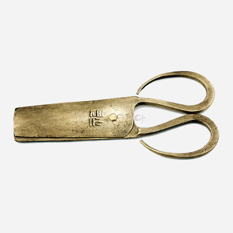 황동빛 금속 재질의 전통 엿가위, 손잡이의 곡선형 디자인과 몸체의 복자 음각 문양이 특징인 공예품.