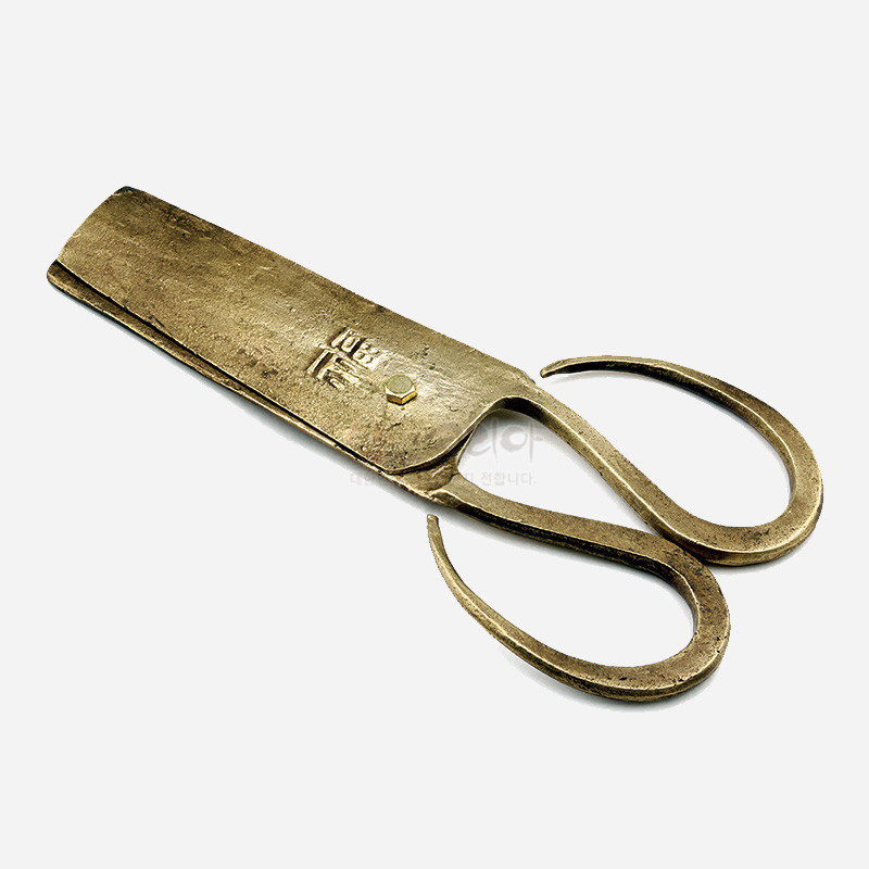 황동빛 금속 재질의 전통 엿가위, 거친 질감과 손잡이의 곡선형 디자인, 몸체에 새겨진 한자 음각 문양이 특징인 공예품.