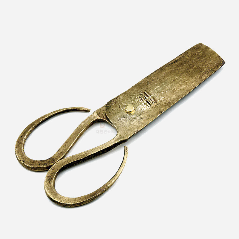 황동 재질의 전통 엿가위 형태, 손잡이 곡선과 투박한 질감, 상단 한글 각인이 특징인 금속 공예품.