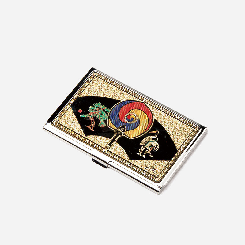 금속 재질 위 금장 바탕에 태극 무늬 부채와 소나무, 학 문양을 섬세한 채색으로 장식한 직사각형 명함케이스.
