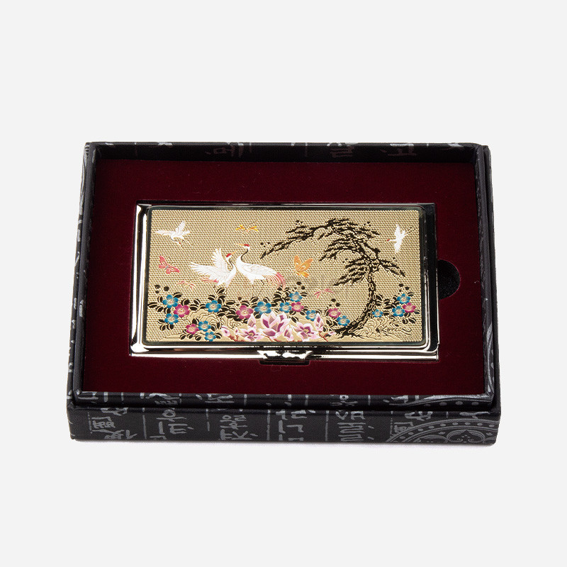 금장 바탕 위에 소나무와 학, 꽃과 나비 문양을 섬세한 채색과 금속 인쇄 기법으로 표현한 금속 명함케이스.