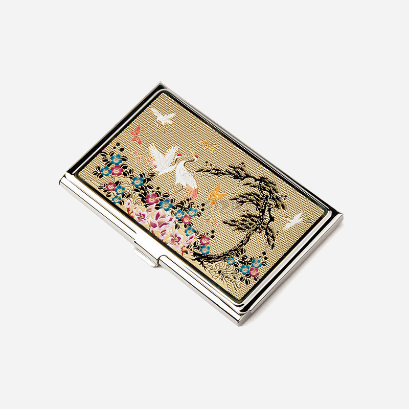 금빛 금속 바탕 위 자개 상감 기법으로 소나무와 학, 화려한 꽃무늬를 배치한 직사각형 명함케이스. 금빛 금속 바탕 위 자개 상감 기법으로 소나무와 학, 화려한 꽃무늬를 배치한 직사각형 명함케이스.