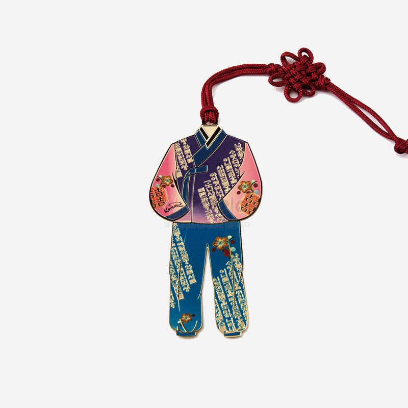 금속 재질에 파스텔톤 한복 모양 채색, 한글 문자와 꽃문양 장식, 붉은 전통 매듭 끈이 연결된 책갈피.