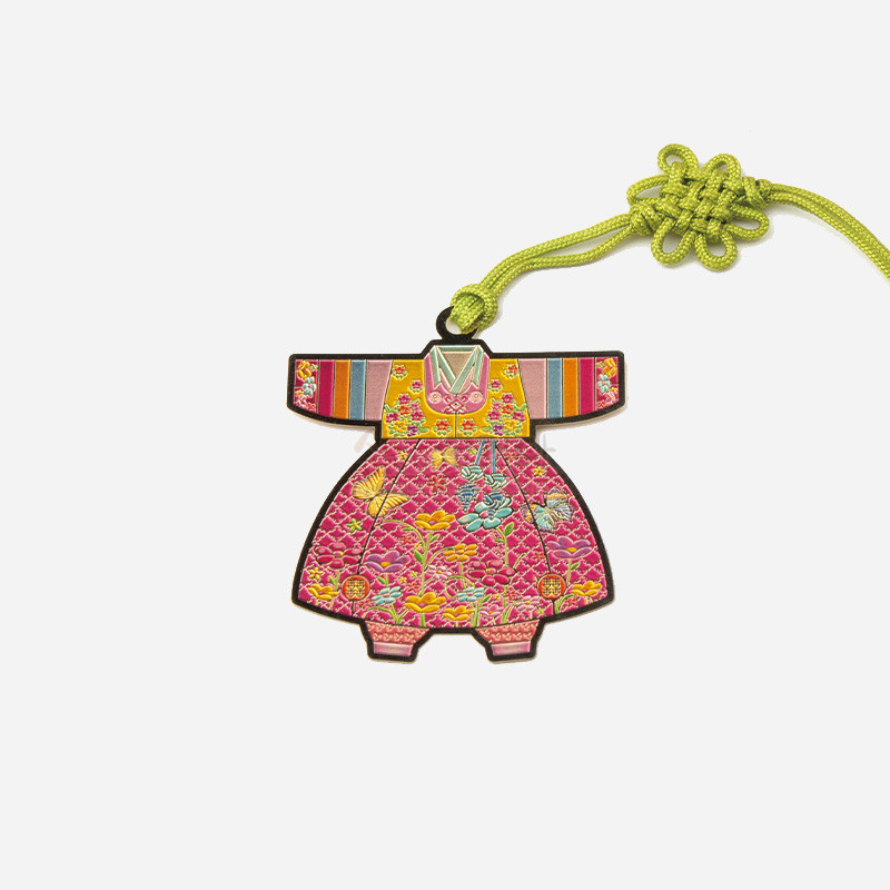 분홍색 아동 한복 형태의 금속 책갈피, 색동 소매와 화려한 꽃문양, 연두색 전통 매듭 끈 장식.