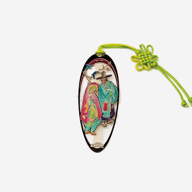 금속 재질에 채색 기법으로 조선시대 인물과 학 문양을 새기고 형광 연두색 전통 매듭 끈을 더한 타원형 책갈피.
