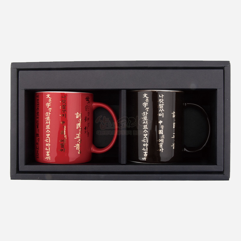 광택 있는 적색·흑색 도자 표면에 금빛 훈민정음 서체가 세로로 인쇄된 머그컵 2종 세트.