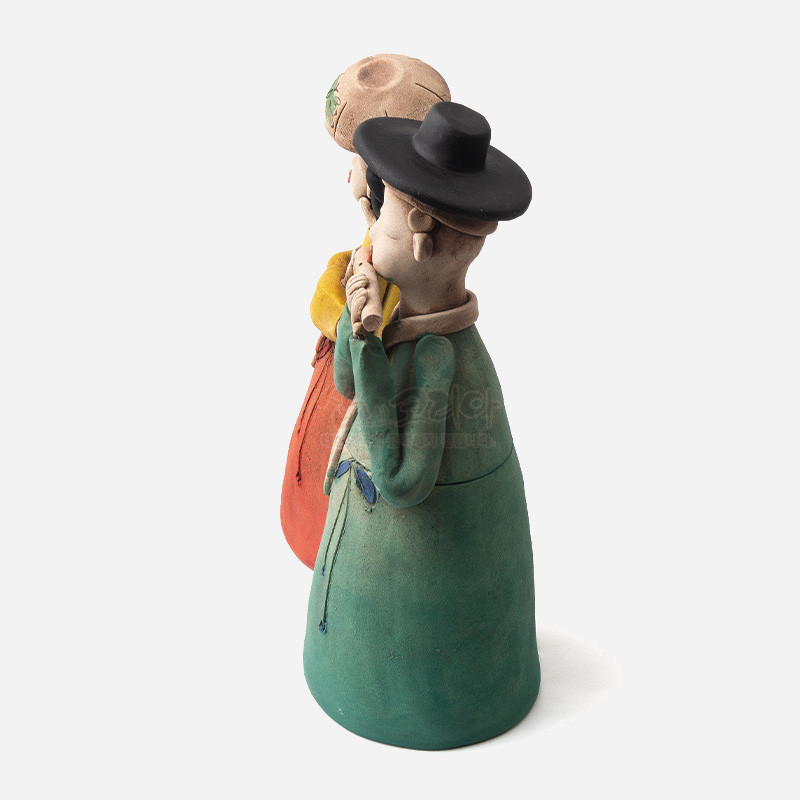 황토 재질로 빚은 선비와 여인 인형, 녹색과 주황색 한복 색채 대비와 검정 갓 장식이 특징인 전통 조형 공예품.