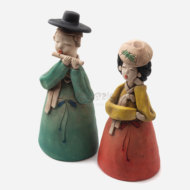 황토 재질로 제작된 선비와 기생 한쌍 인형, 녹색과 적색 한복의 은은한 채색과 단순화된 전통 복식 표현이 특징인 장식품.