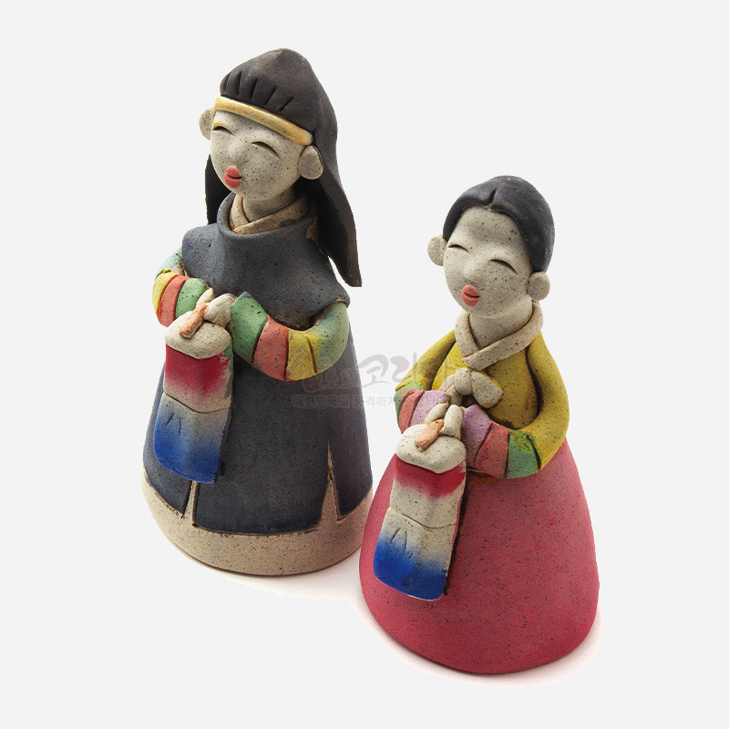 황토 질감의 도자 재질로 제작된 전통복 한복 인형, 오방색 저고리와 청사초롱을 든 단순화된 조형미가 특징인 장식 인형. 황토 질감의 도자 재질로 제작된 전통복 한복 인형, 오방색 저고리와 청사초롱을 든 단순화된 조형미가 특징인 장식 인형.