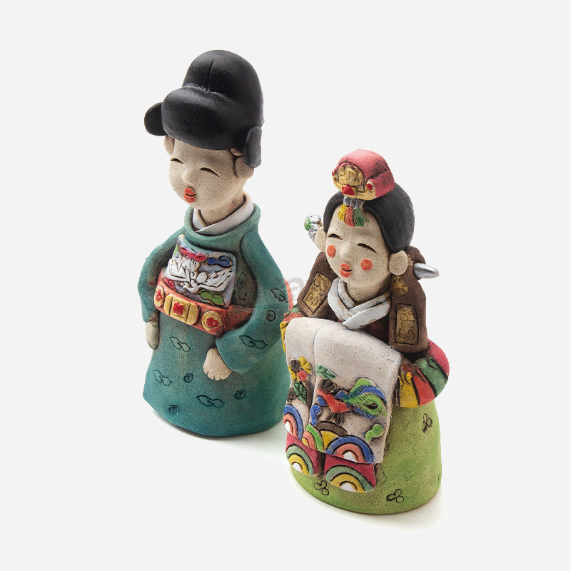 채색 황토 재질로 만든 전통 혼례복 신랑신부 인형, 오방색과 봉황·무지개 문양이 돋보이는 수공예 장식.