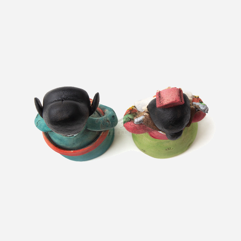 황토 재질의 신랑신부 인형으로, 검은 쪽머리와 색동 한복, 녹색·청록·적색의 채색이 돋보이는 전통 혼례 장식 인형.