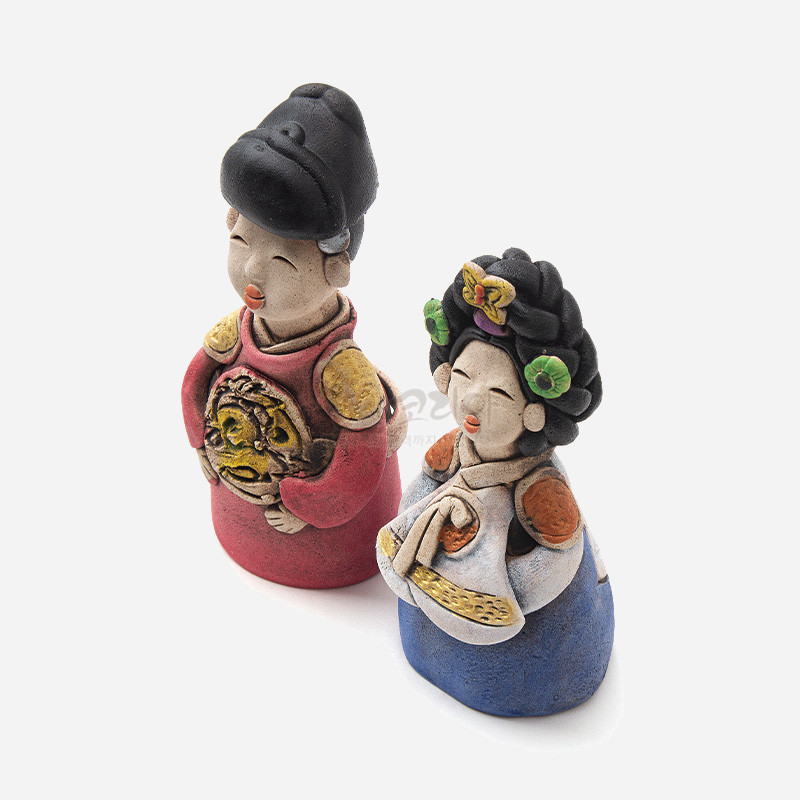 황토 느낌의 소박한 질감이 강조된 작은 왕과 왕비 인형, 붉은색·청색 의상과 화려한 머리장식, 금색 문양 장식 특징.