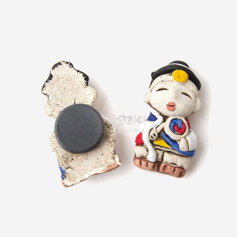 황토 느낌의 거친 질감 도자 재질에 농악 복장을 입은 인형 형상의 냉장고 자석, 빨강·파랑·노랑 포인트 색채 장식.