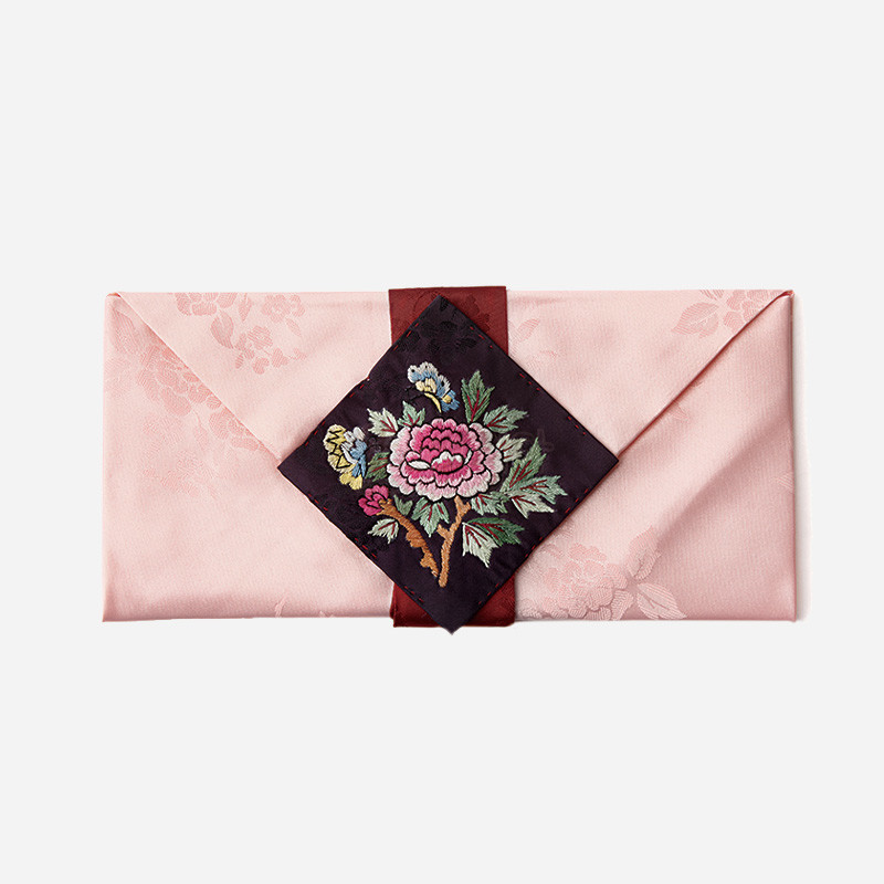연분홍색 비단에 은은한 꽃문양이 짜여 있고, 중앙 자주색 장식에 자수로 목단 꽃과 잎사귀가 수놓인 봉투형 예단보. 연분홍색 비단에 은은한 꽃문양이 짜여 있고, 중앙 자주색 장식에 자수로 목단 꽃과 잎사귀가 수놓인 봉투형 예단보.