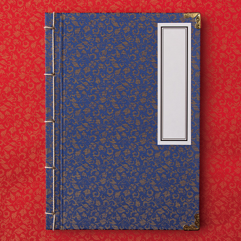 청색 비단 천 위에 금색 꽃무늬가 짜인 표지와 황동 모서리 장식, 전통 오침 제본이 특징인 노트.