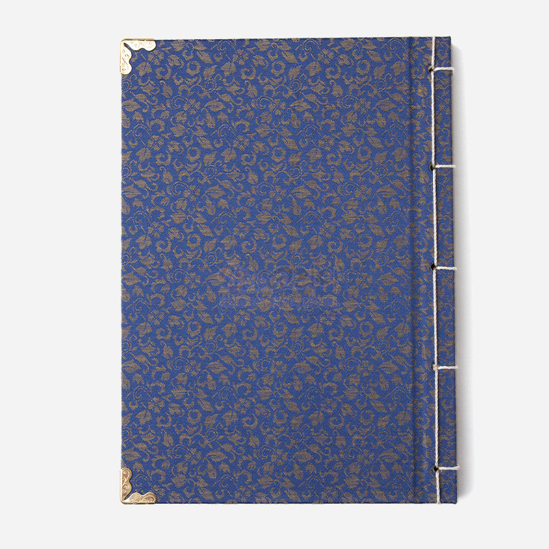 청색 비단에 금색 꽃무늬 직조와 전통 오침 바느질, 금속 모서리 장식이 특징인 노트.
