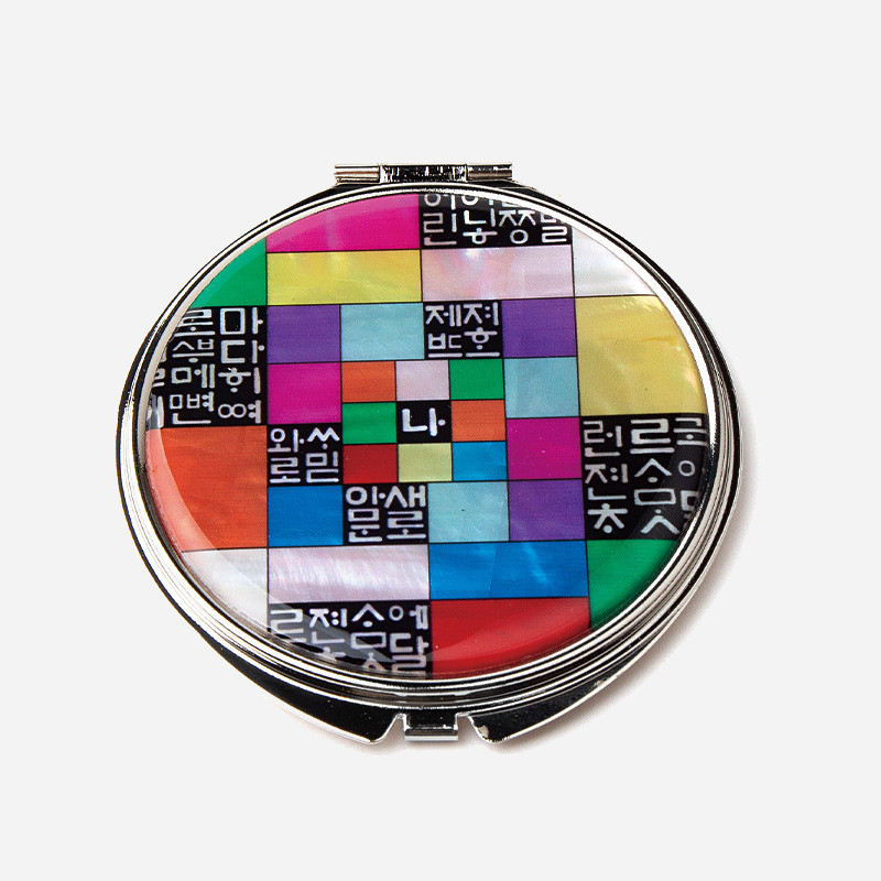자개와 금속으로 제작된 원형 손거울, 다채로운 조각보 배열 위에 훈민정음 글자를 조합한 모던한 자개장식 손거울.