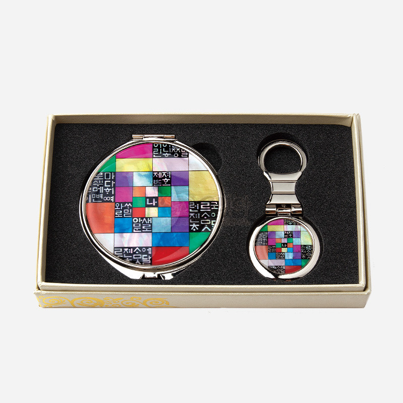 자개 상감과 옻칠 기법으로 제작된 금속 손거울과 키링 세트, 다채로운 조각보 배경 위에 훈민정음 문자 문양이 어우러진 디자인.