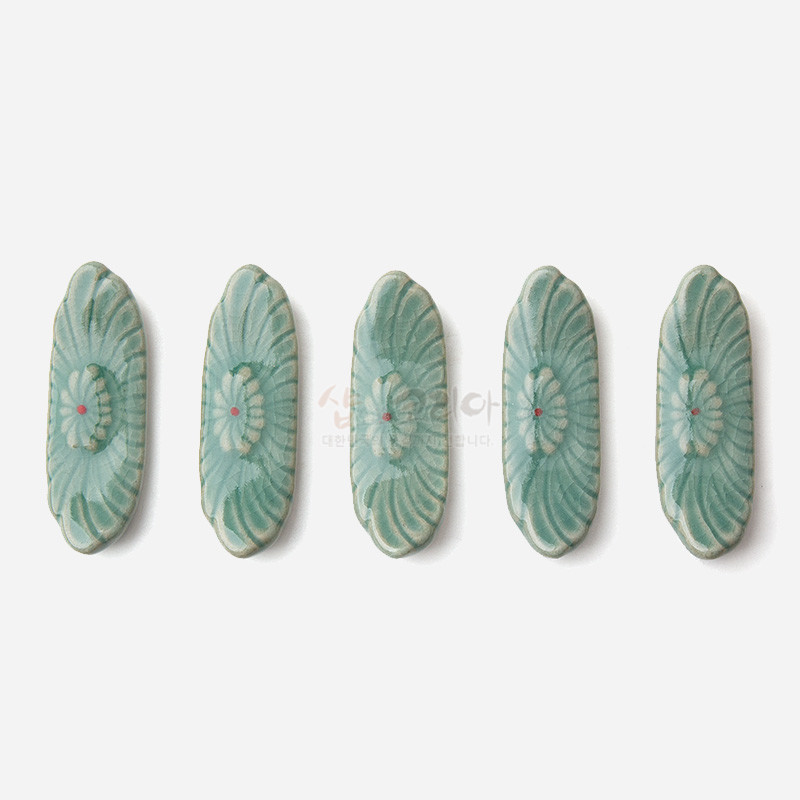 청자 재질의 타원형 수저받침에 양각으로 표현된 꽃무늬와 옅은 비취색 유약, 중앙의 붉은 점 장식이 조화를 이루는 5종 세트. 청자 재질의 타원형 수저받침에 양각으로 표현된 꽃무늬와 옅은 비취색 유약, 중앙의 붉은 점 장식이 조화를 이루는 5종 세트.