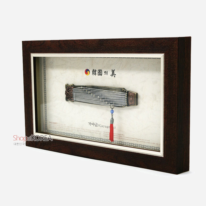 나무 재질의 액자에 금속 가야금 모형과 청색 구슬·홍색 술 장식을 더한 전통 악기 장식 액자.