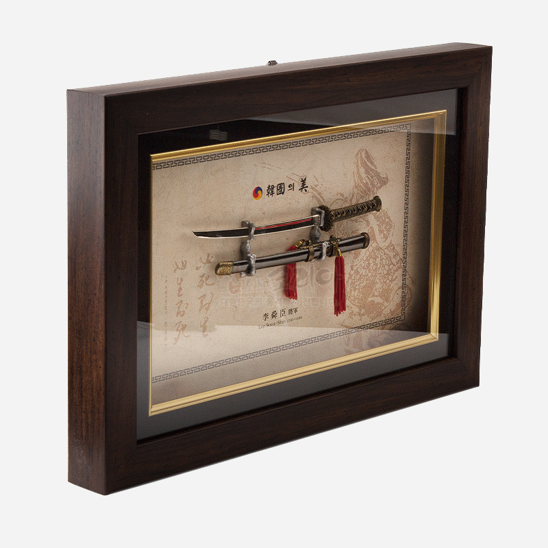 목재 액자 속 금속 이순신 장검 모형과 붉은 술 장식, 전통 문양 배경지가 어우러진 입체 액자형 장식.