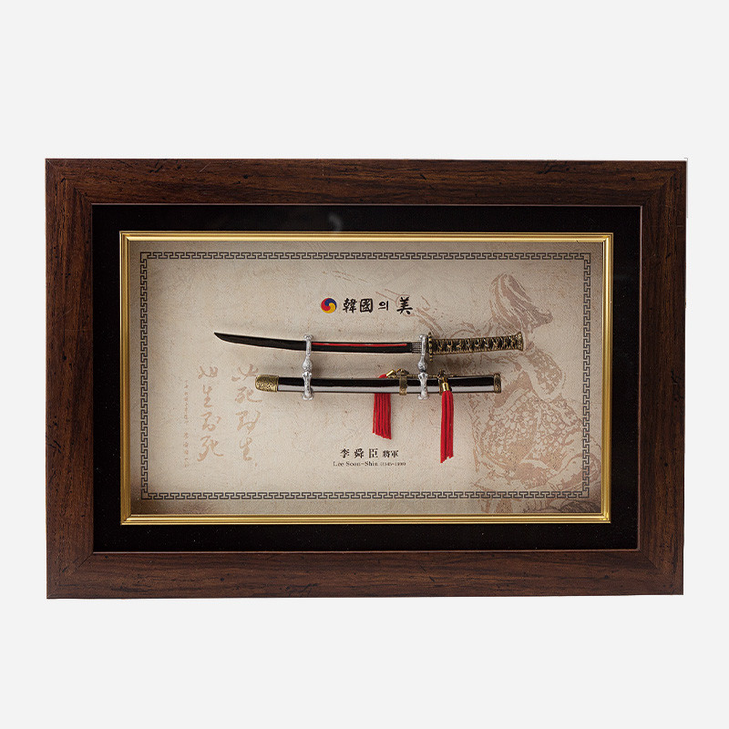 나무 테두리 액자 속 금속 장검 모형과 칼집, 적색 술 장식, 전통 문양 배경지가 조화된 이순신 장검 액자형 장식품.