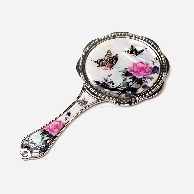 자개 바탕 위에 옻칠 채색으로 담화와 나비 문양을 표현한 금속 테두리 손잡이 거울.