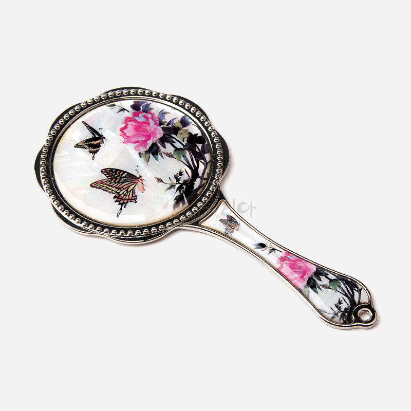 자개 바탕 위에 분홍 꽃과 나비 문양을 채색한 금속 테두리 손잡이 거울.