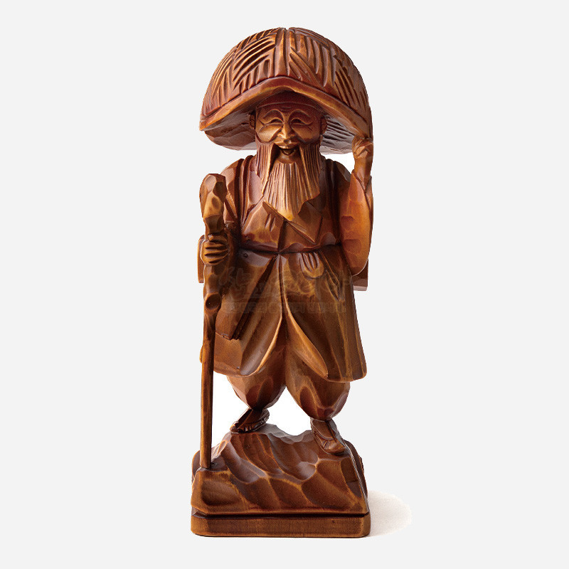나뭇결이 살아 있는 원목 재질에 정교한 조각 기법으로 삿갓과 지팡이, 주름진 의복을 표현한 갈색 목각 인형.