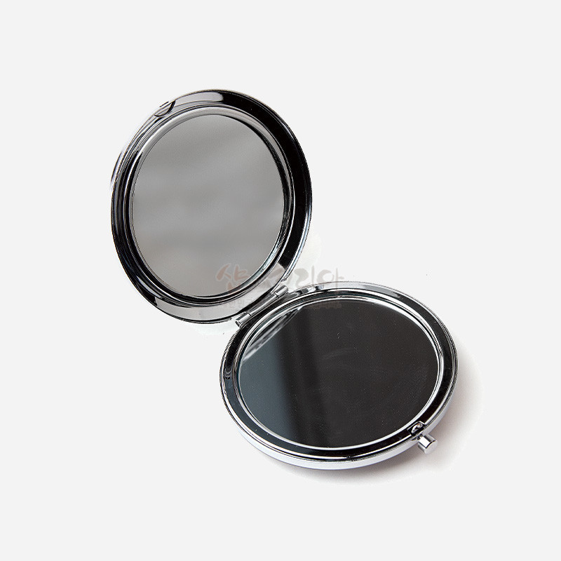 은색 금속 재질의 원형 양면 거울, 매끈한 광택 마감과 간결한 무지 디자인의 휴대용 손거울.