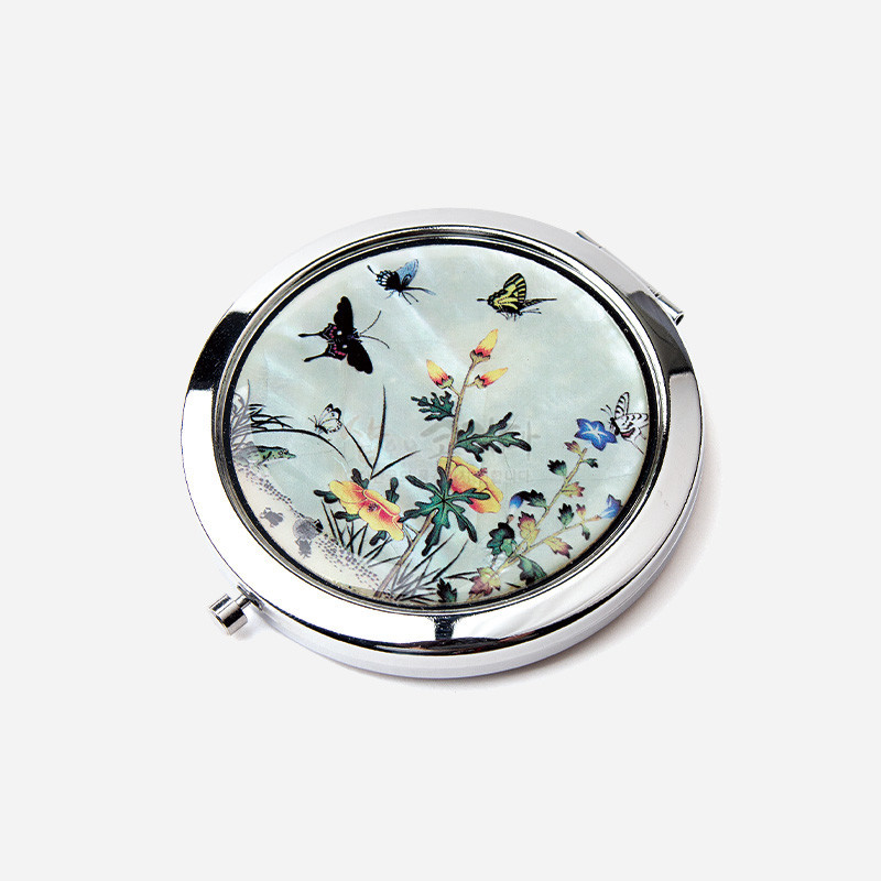 자개 상감 기법으로 꽃과 풀, 나비와 매미가 섬세하게 표현된 초충도 문양의 금속 테두리 원형 손거울.