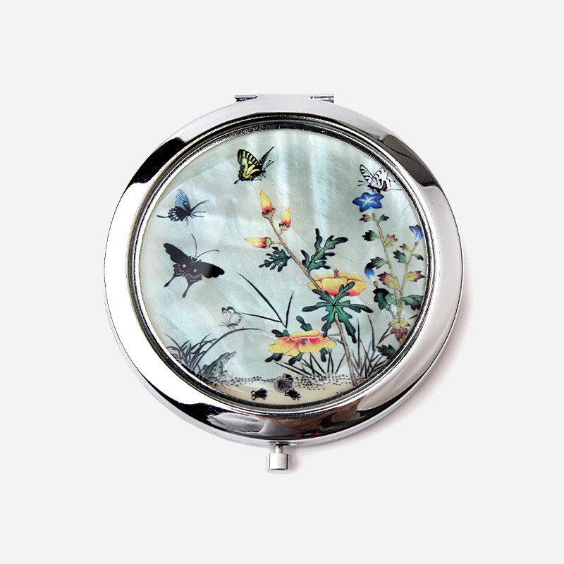 자개 상감 기법으로 꽃과 나비, 풀벌레 초충도 문양을 섬세하게 표현한 원형 금속 손거울.