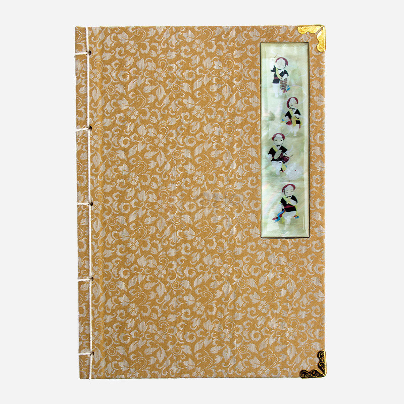 황금색 비단에 꽃문양이 놓인 표지와 사물놀이 인물 자개 상감 장식, 금속 모서리 장식이 있는 오침식 노트.