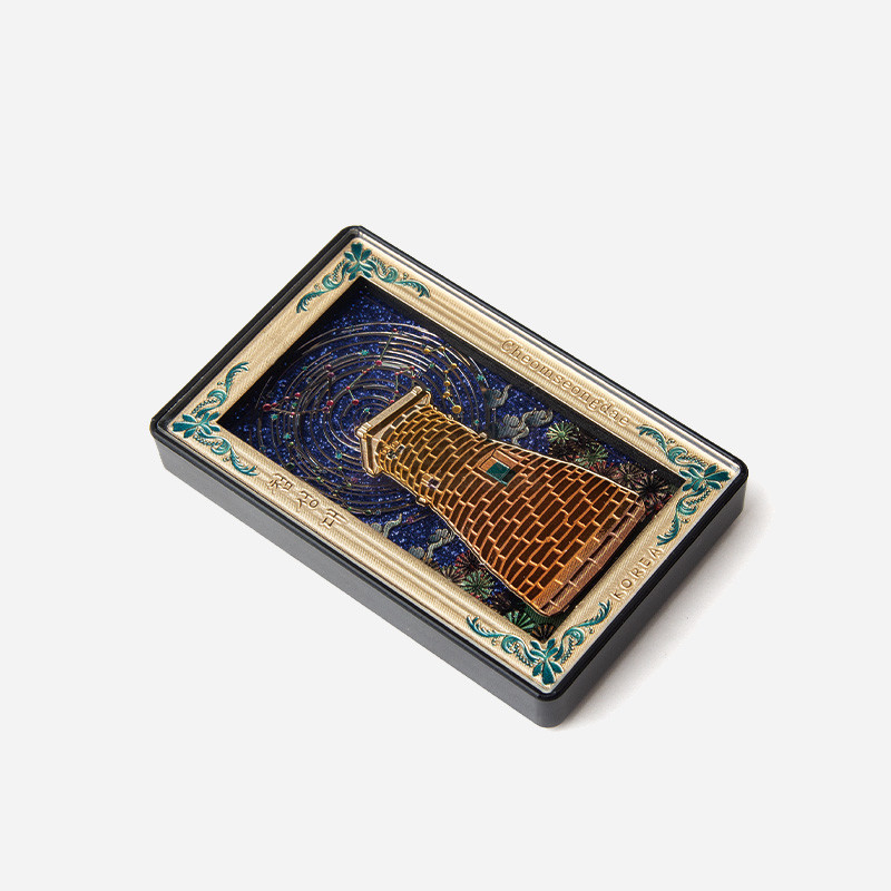 금속 재질로 표현한 첨성대 입체 형상과 청록색 장식 테두리, 밤하늘 별자리 문양이 어우러진 직사각형 마그넷.