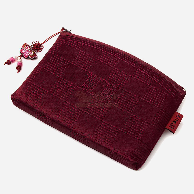 적갈색 비단 누비 처리와 격자 문양, 중앙 전통 문자 문양, 나비 매듭 장식 지퍼 손잡이가 특징인 파우치.